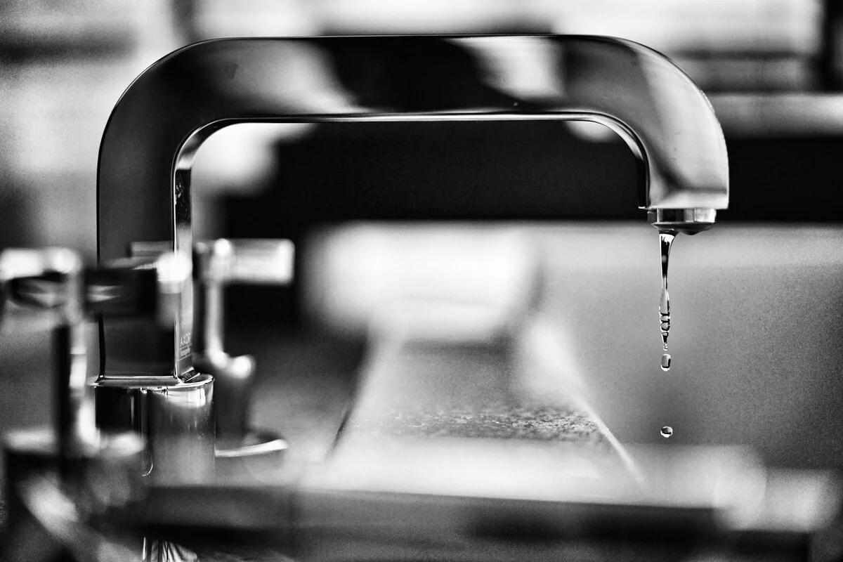 Druppelende chromen keukenkraan met zichtbare waterlekkage